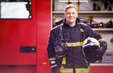 Photo of happy male firefighter with helmet in his hands against Photo of happy male firefighter with helmet in his hands against